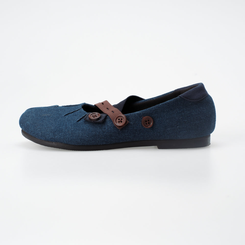 Denim blue flat shoe with brown button details on a white background