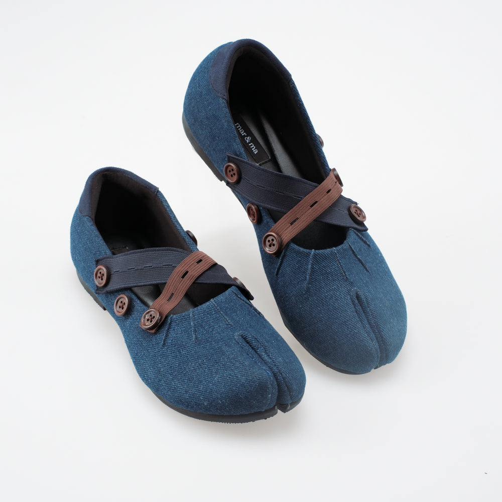 Denim blue flat shoes with brown and black straps on a white background