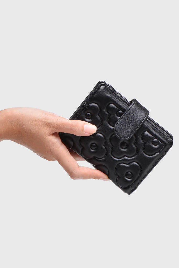 Black textured wallet by Adorable Projects held by a hand on a light gray background