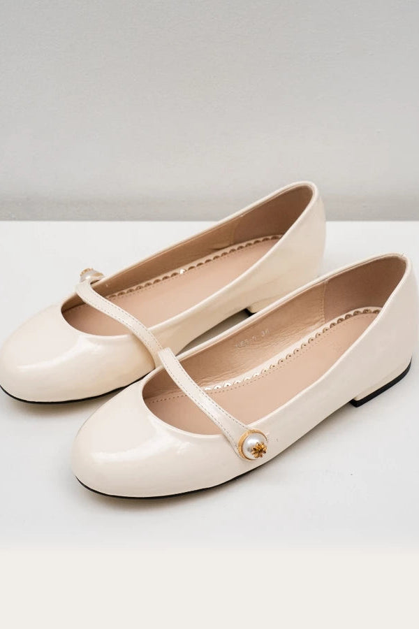 Pair of beige flat shoes with a strap on a white background