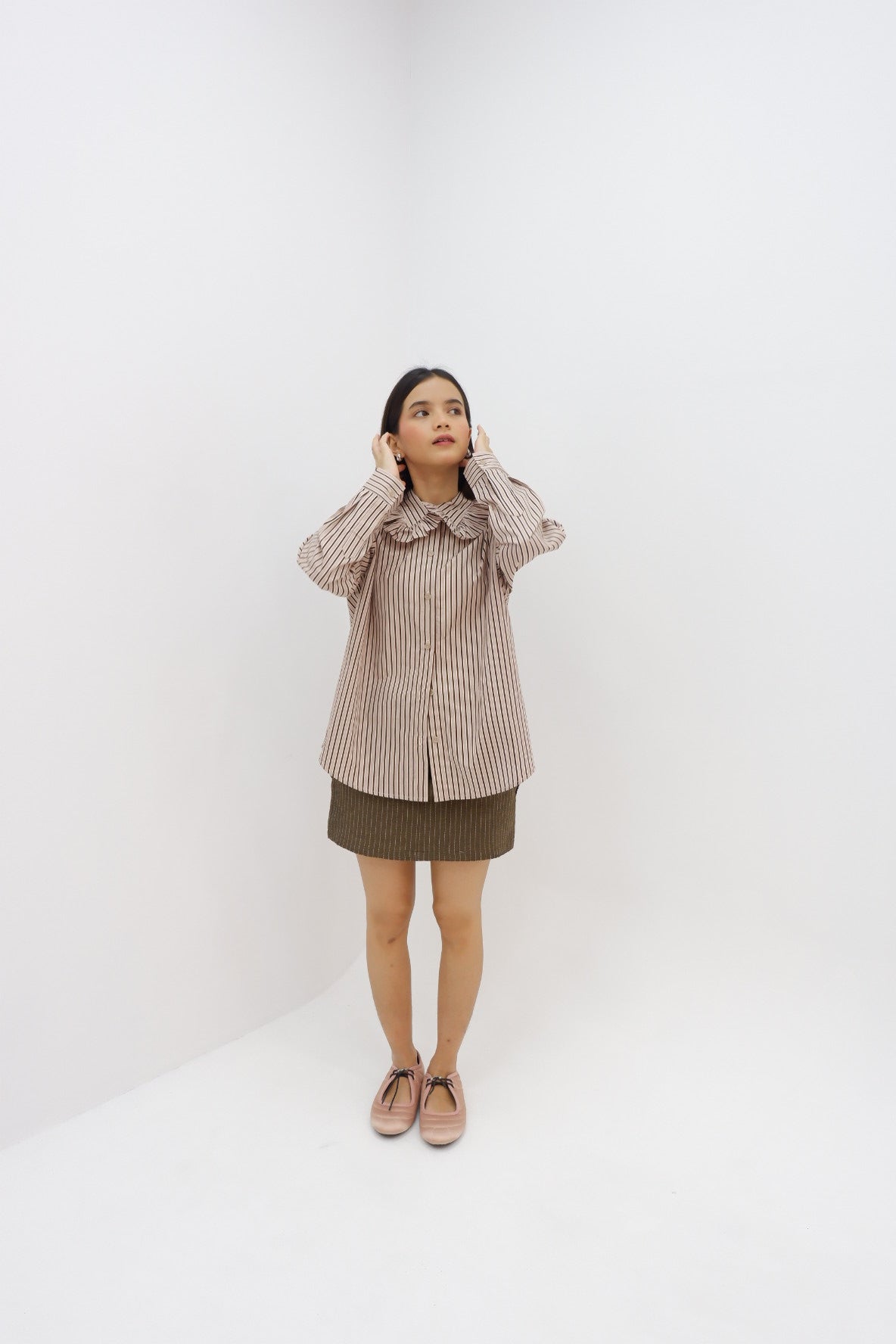 Person wearing a brown striped shirt by Tuff Puff and skirt on a white background