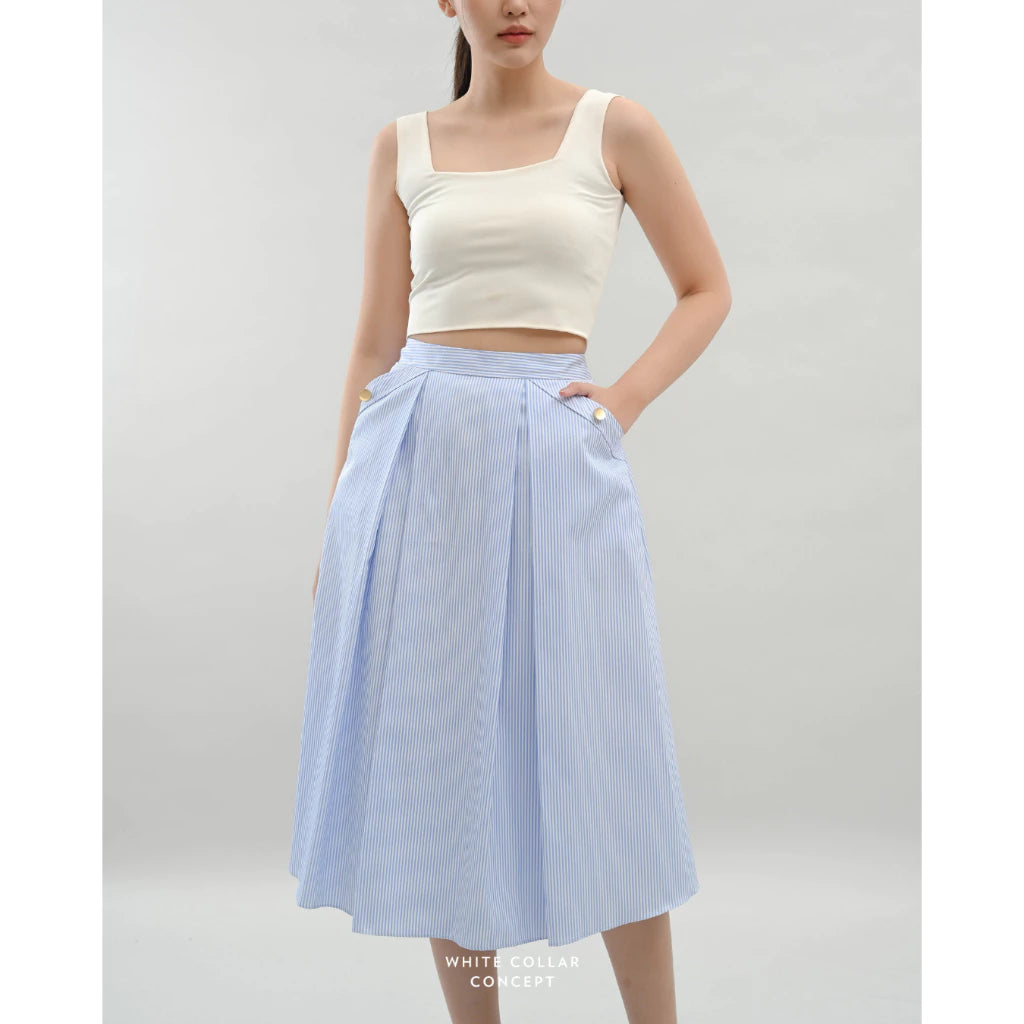 Woman wearing a white top and light blue skirt on a plain background