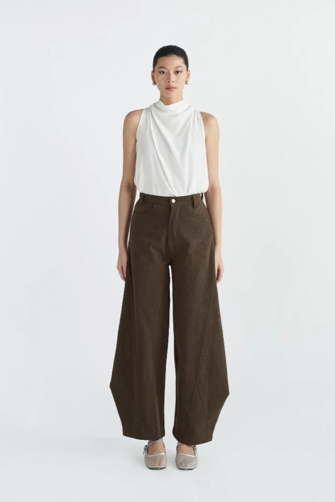 Person wearing a white sleeveless top and brown wide-leg pants by Achete de Nous on a white background