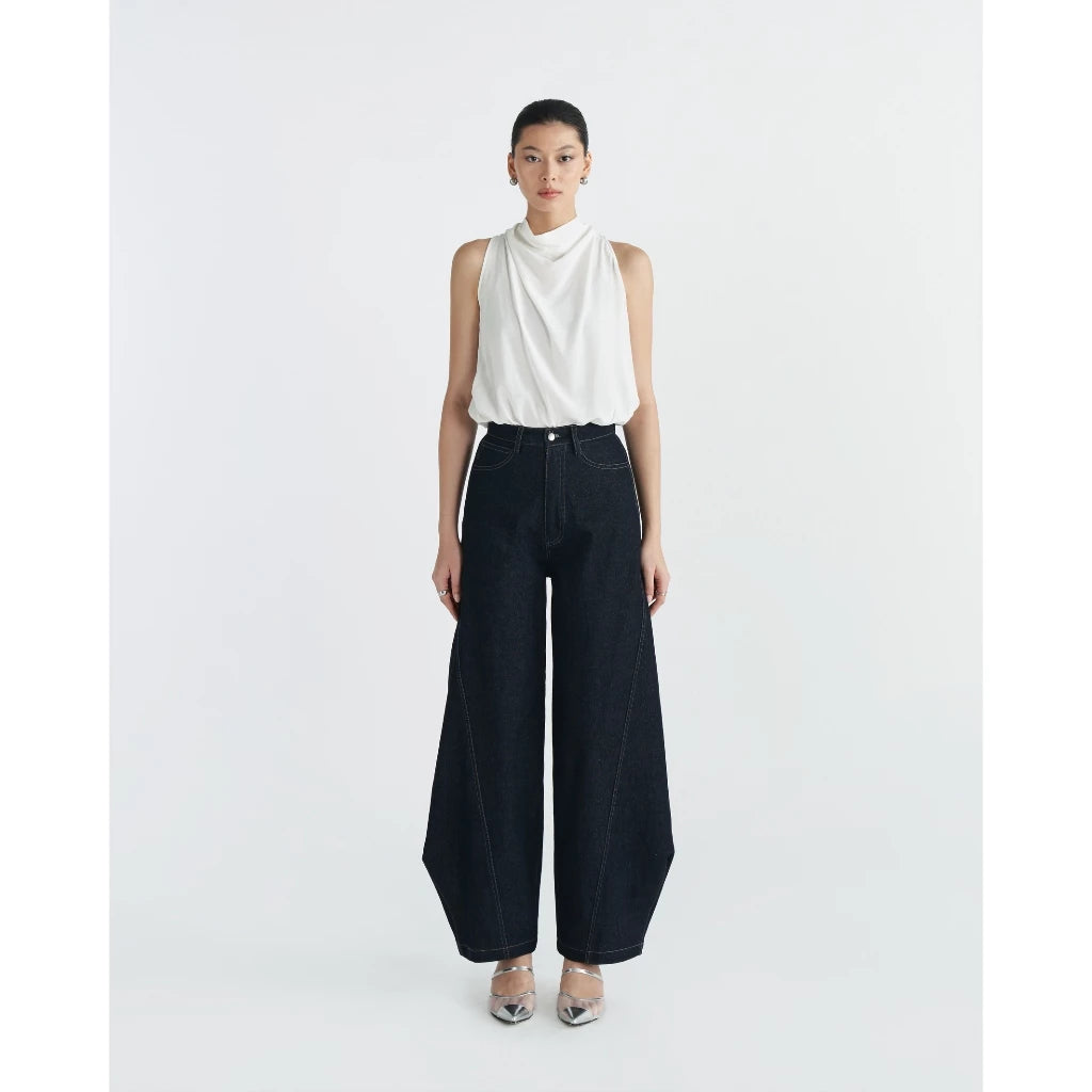 Woman wearing a white sleeveless top and dark blue wide-leg pants by Achete de Nous on a white background