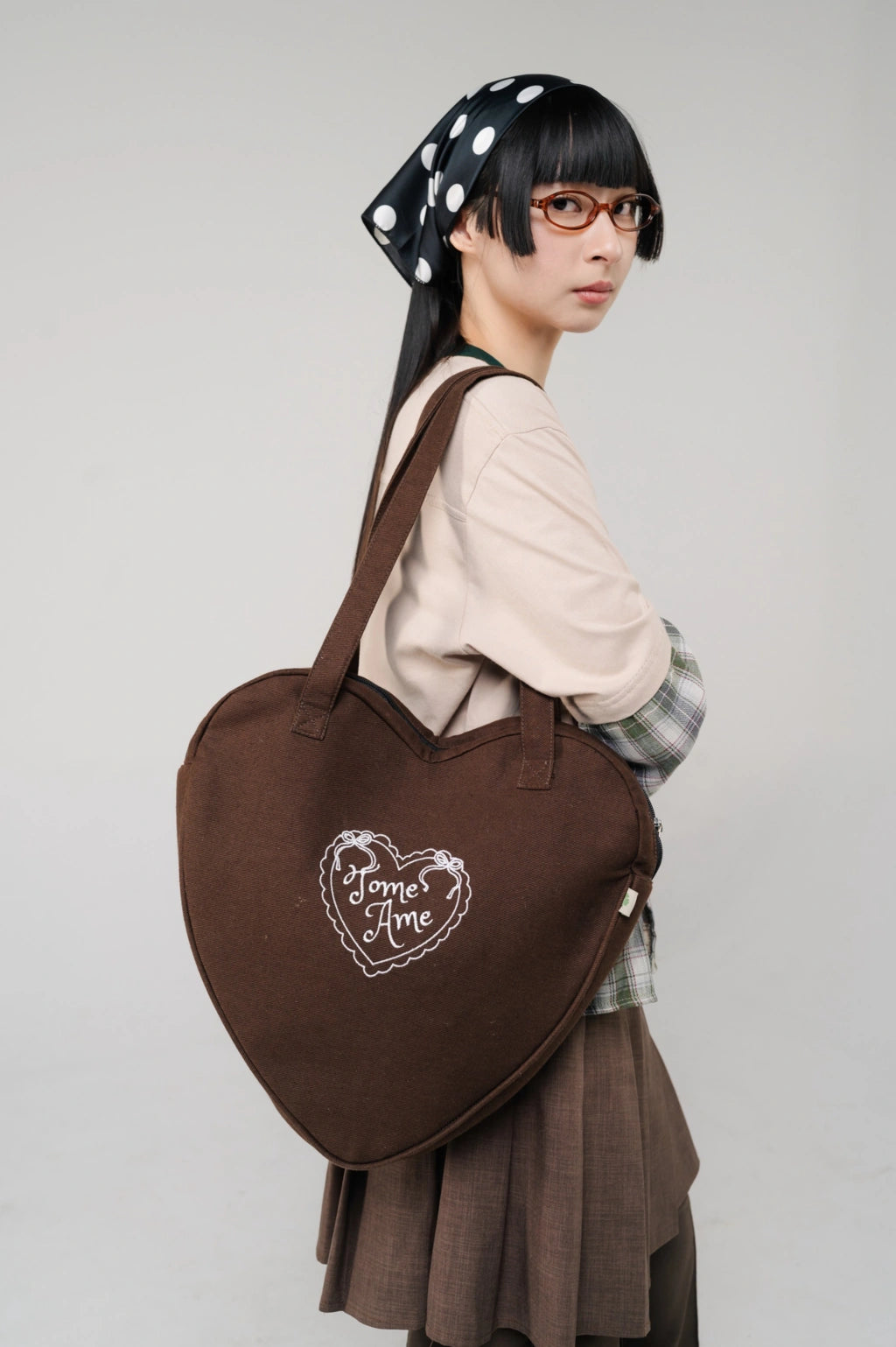 Person wearing a large brown heart-shaped Tome Ame tote bag
