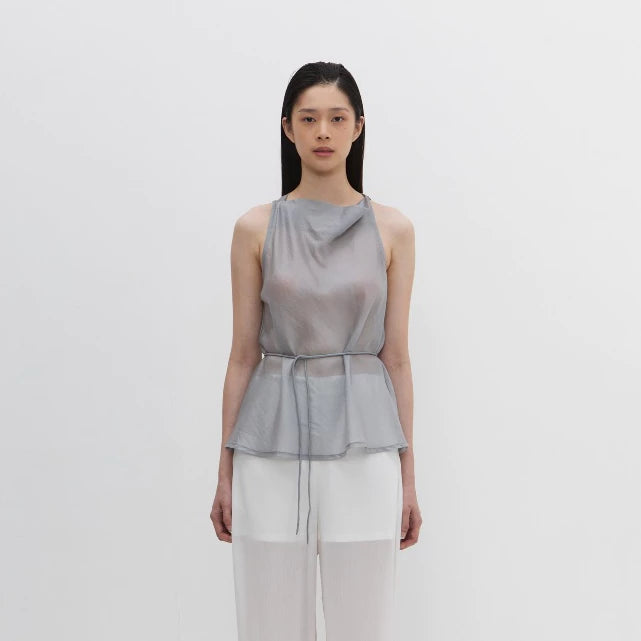 Woman wearing a sleeveless gray blouse by Morningsol with a draped design on a white background