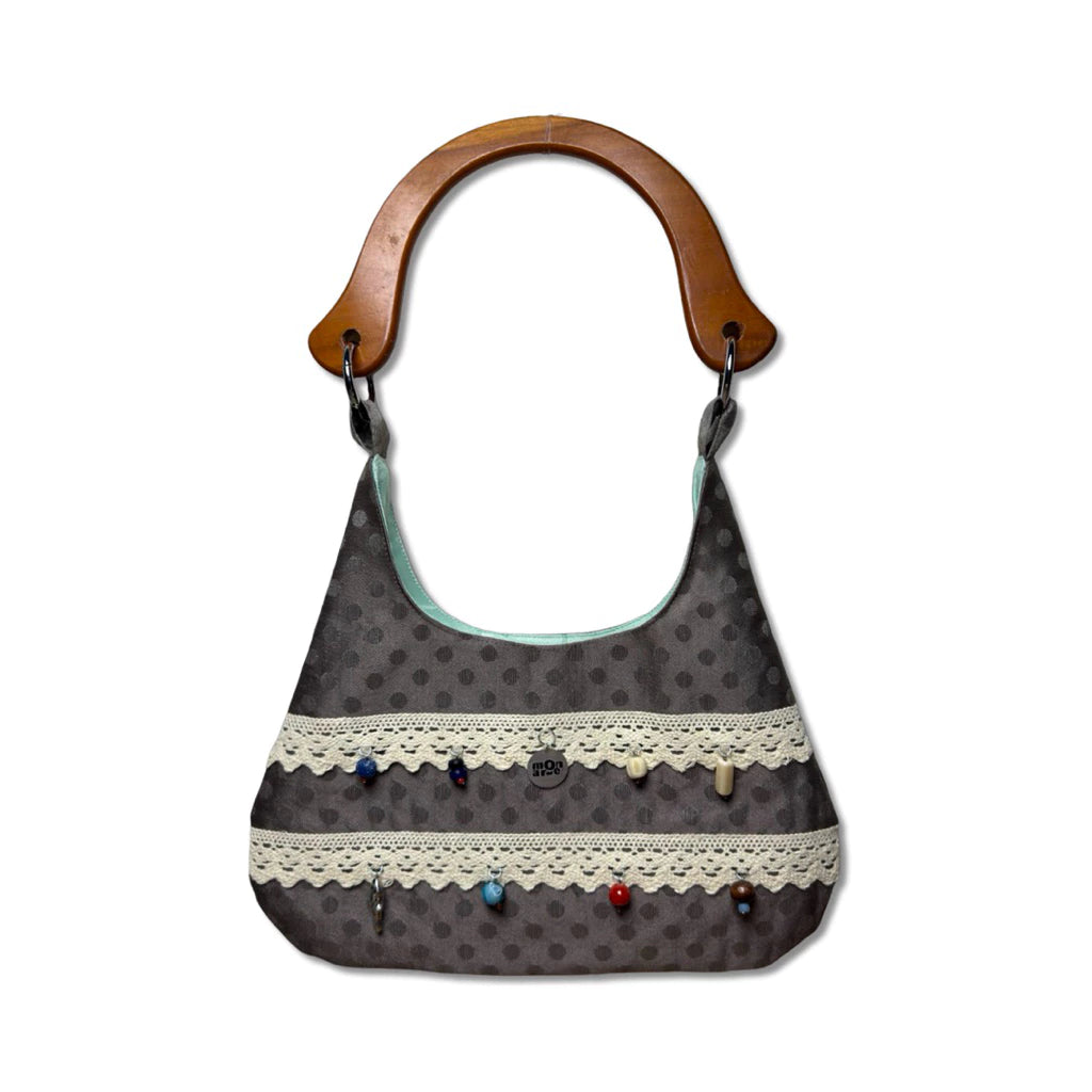Women's handbag with polka dot pattern and wooden handle on a white background
Tas tangan wanita bermotif polkadot dengan pegangan kayu pada latar belakang putih