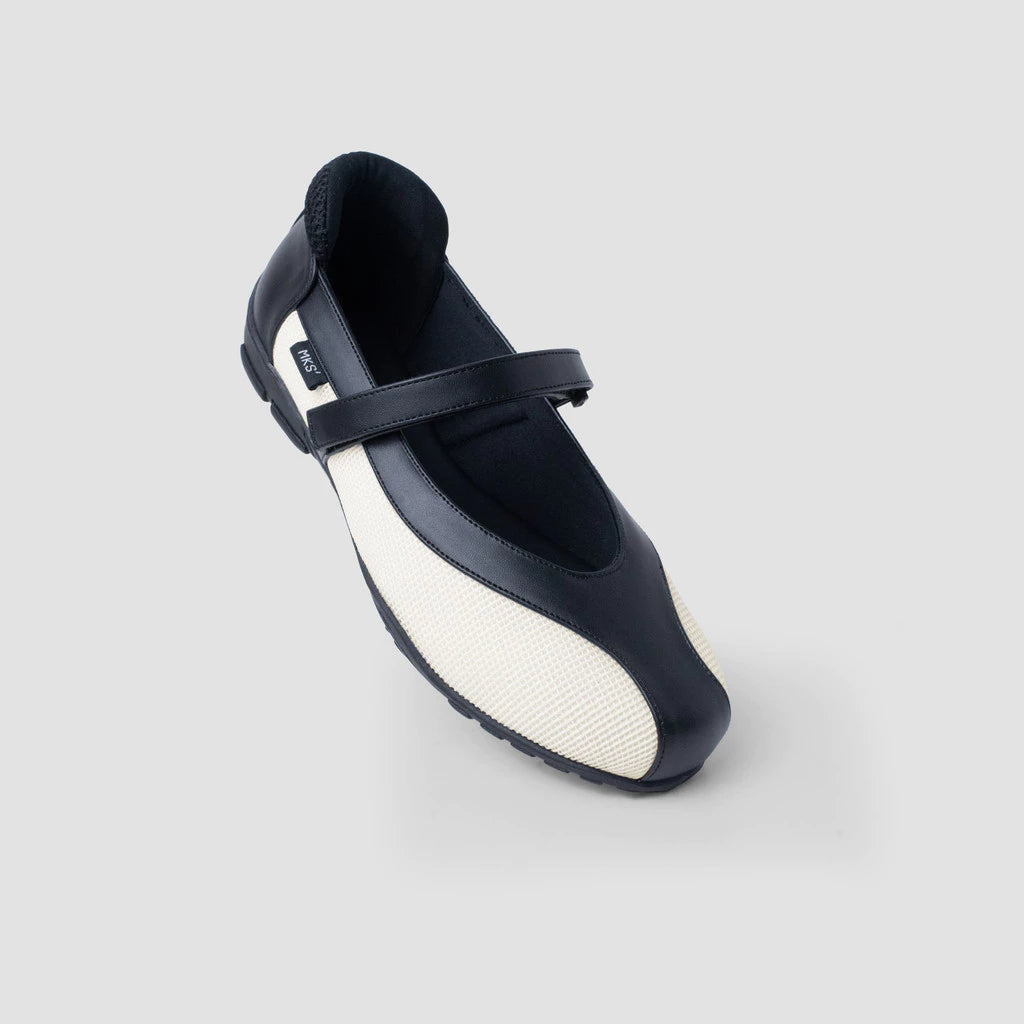 A white and black flat shoes by MKS Shoes with a Mary Jane strap and a low heel, set on a white background.