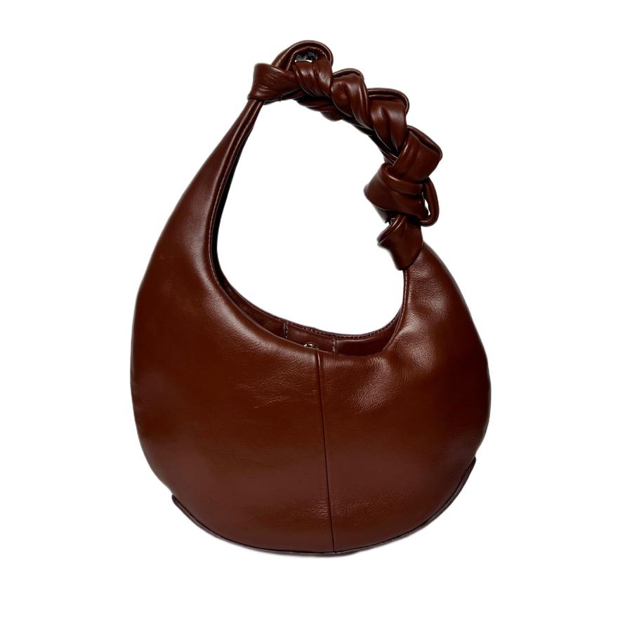 Brown leather handbag with knotted handle on a white background
Tas tangan wanita berbahan kulit berwarna cokelat dengan pegangan yang diikat pada latar belakang putih