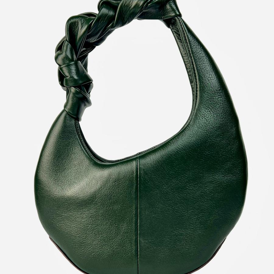 Green leather handbag with knotted handle on a white background
Tas tangan wanita berbahan kulit berwarna hijau dengan pegangan yang diikat pada latar belakang putih