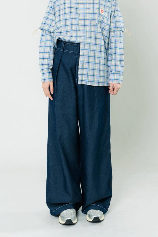 Person wearing a blue plaid shirt and wide-leg navy denim pants by notyourcompany on a plain background