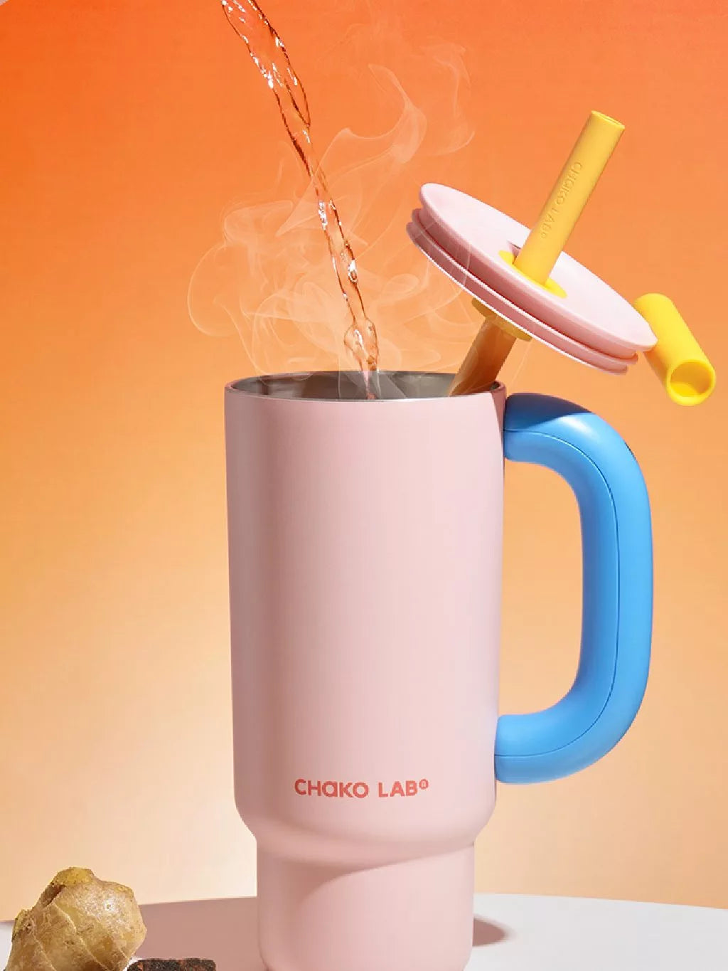 A pink Chako Lab Baba Cup with a blue handle and a yellow straw filled with hot water.