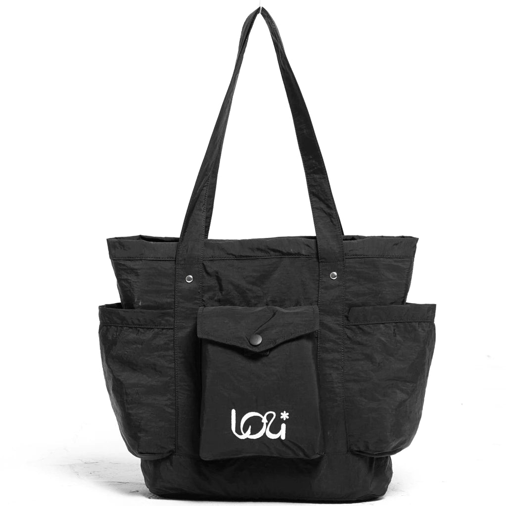 Black women’s tote bag featuring two long handles, a front flap pocket with button closure, and two spacious side pockets.
Tas wanita warna hitam dengan desain tote bag, dilengkapi dua handle panjang, satu kantong depan berpenutup kancing, serta dua kantong samping yang luas.