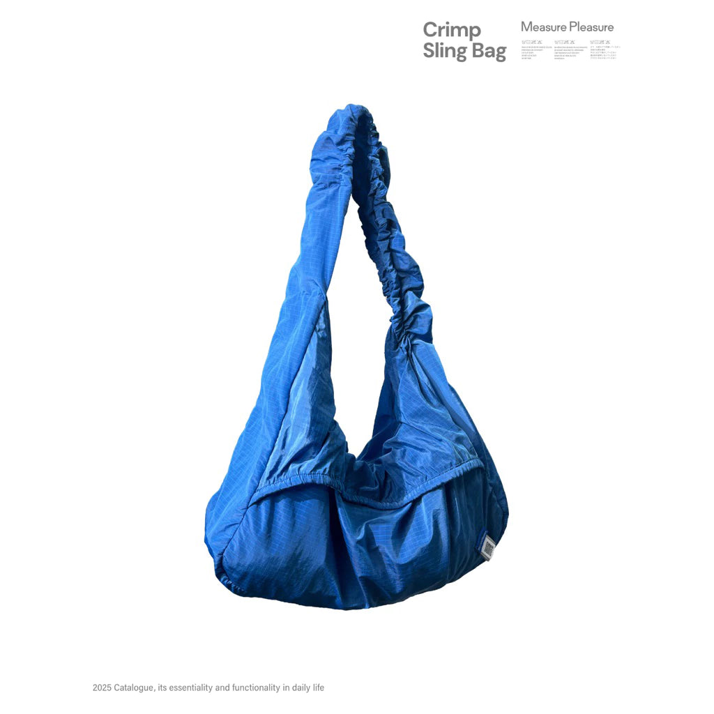 Blue sling bag by Measure Pleasure with a visible brand label on a white background