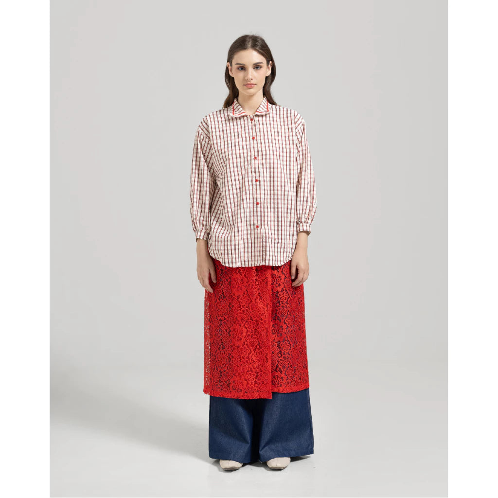 Woman wearing a red checkered shirt by Tuff Puff, red lace skirt, and blue pants on a gray background