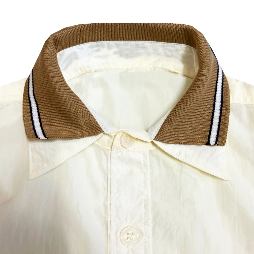 Close-up of a beige polo shirt by Hunting Fields with a brown collar and white stripes on a white background