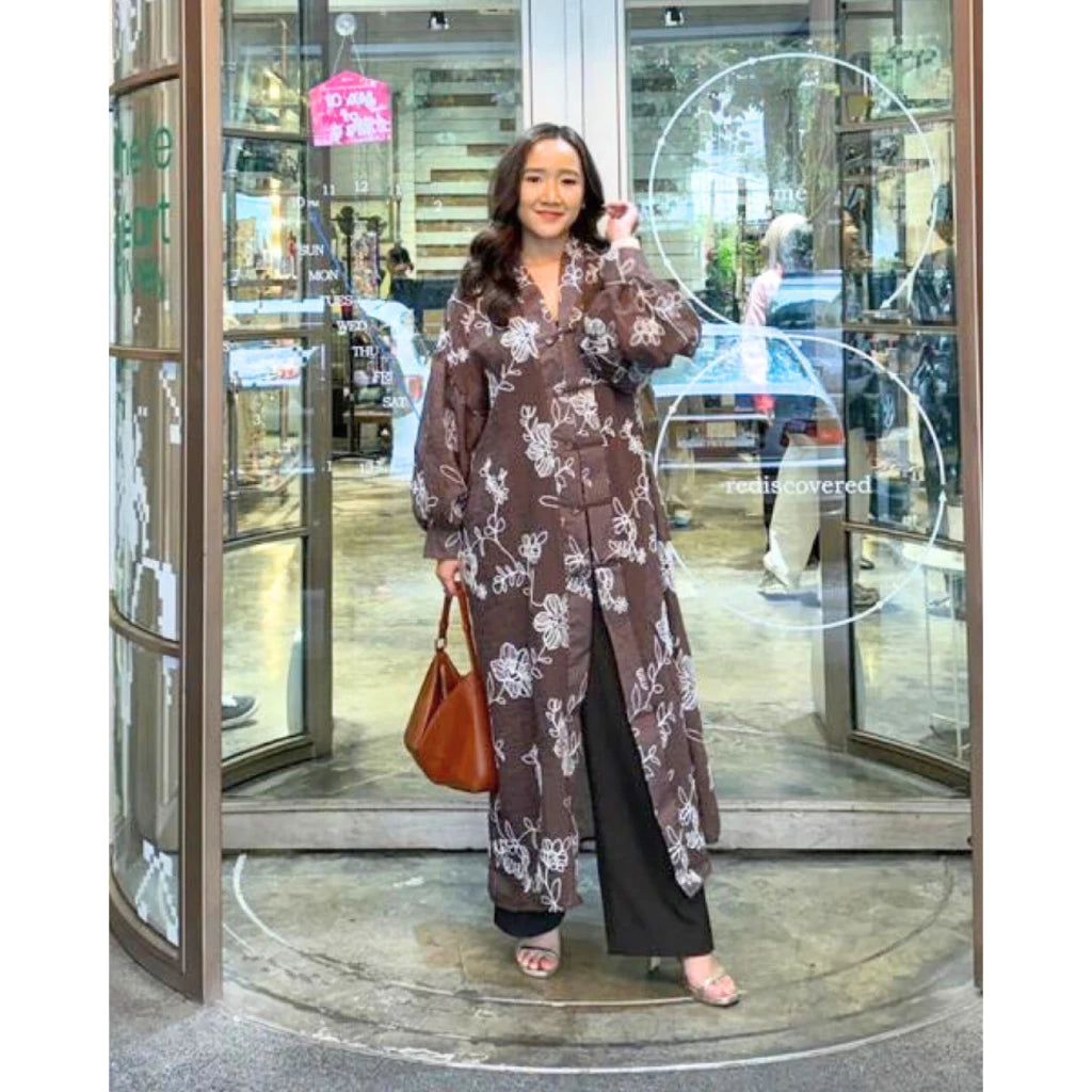 Woman in a floral dress by Tuff Puff standing in front of a glass door.
