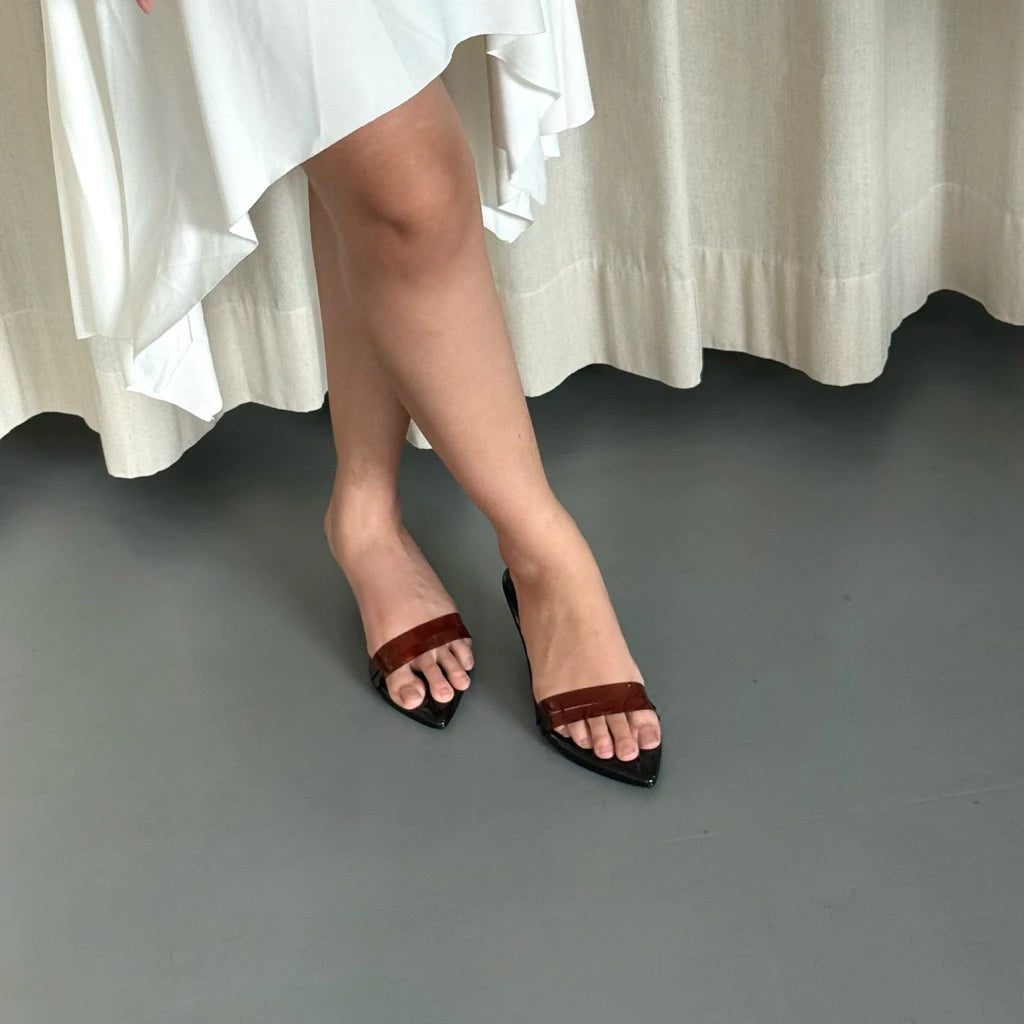 Person wearing brown sandals by Takkan on a gray floor with white fabric in the background
