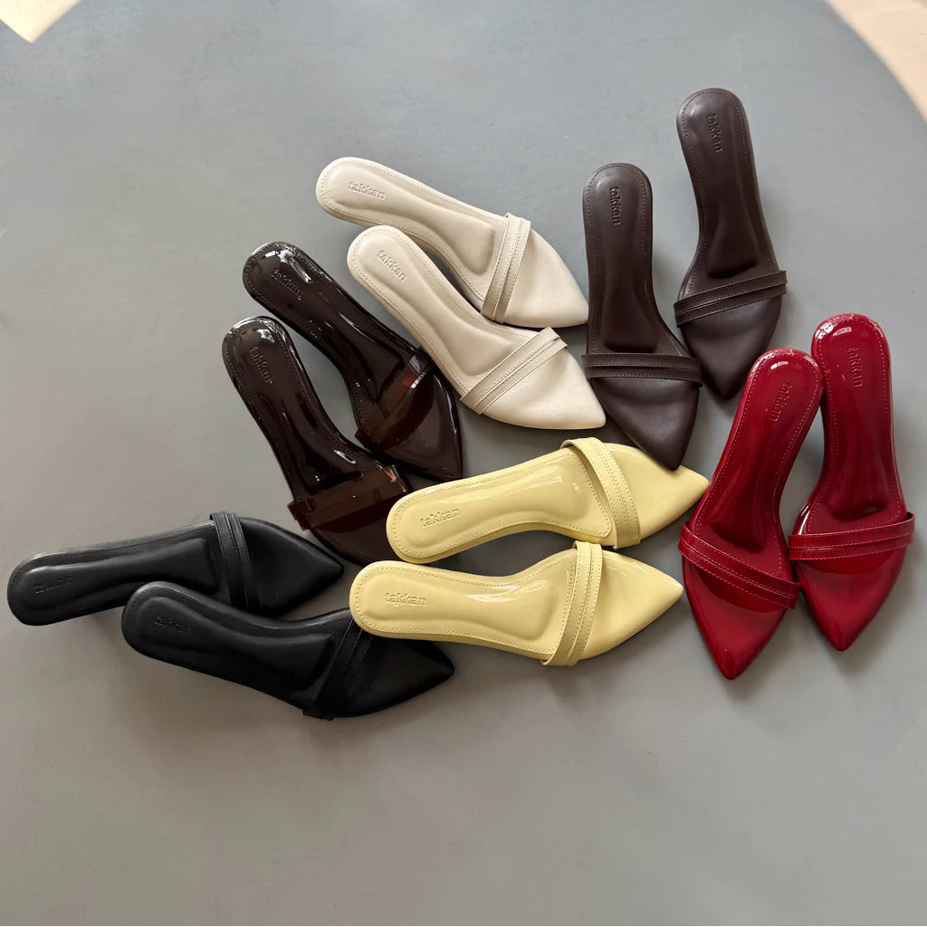 Set of women's pointed-toe heels in black, brown, beige, red, and yellow by Takkan on a gray surface.