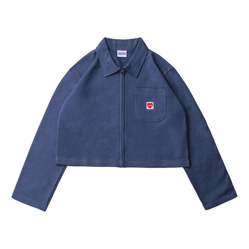 A dark blue crop jacket with a collar, long sleeves, and a front pocket, featuring a small red logo on the chest by notyourcompany.