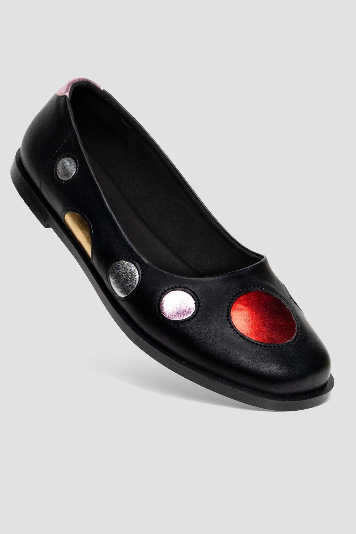 A black leather ballet flat shoe by MKS featuring decorative circular cutouts in red, silver, gold, and pink on the side, shown against a light gray background.