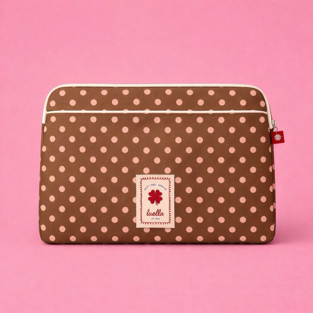 Light brown polka dot laptop sleeve by Luella with a brand label on a pink background