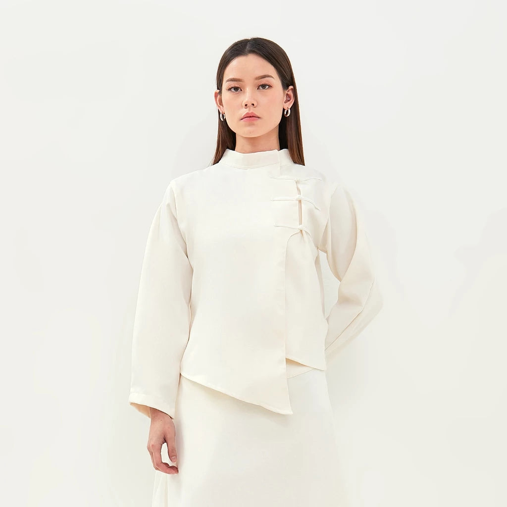 Woman wearing a white top by Isoos Studios against a plain background