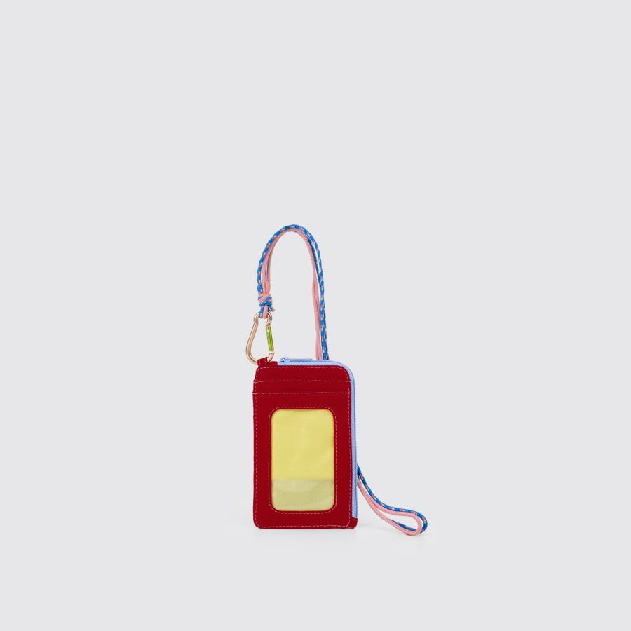 A red nylon lanyard card holder with a pink and blue strap and a clear front card slot, featuring a carabiner and a 43 cm long neck strap from Exsport Bags.