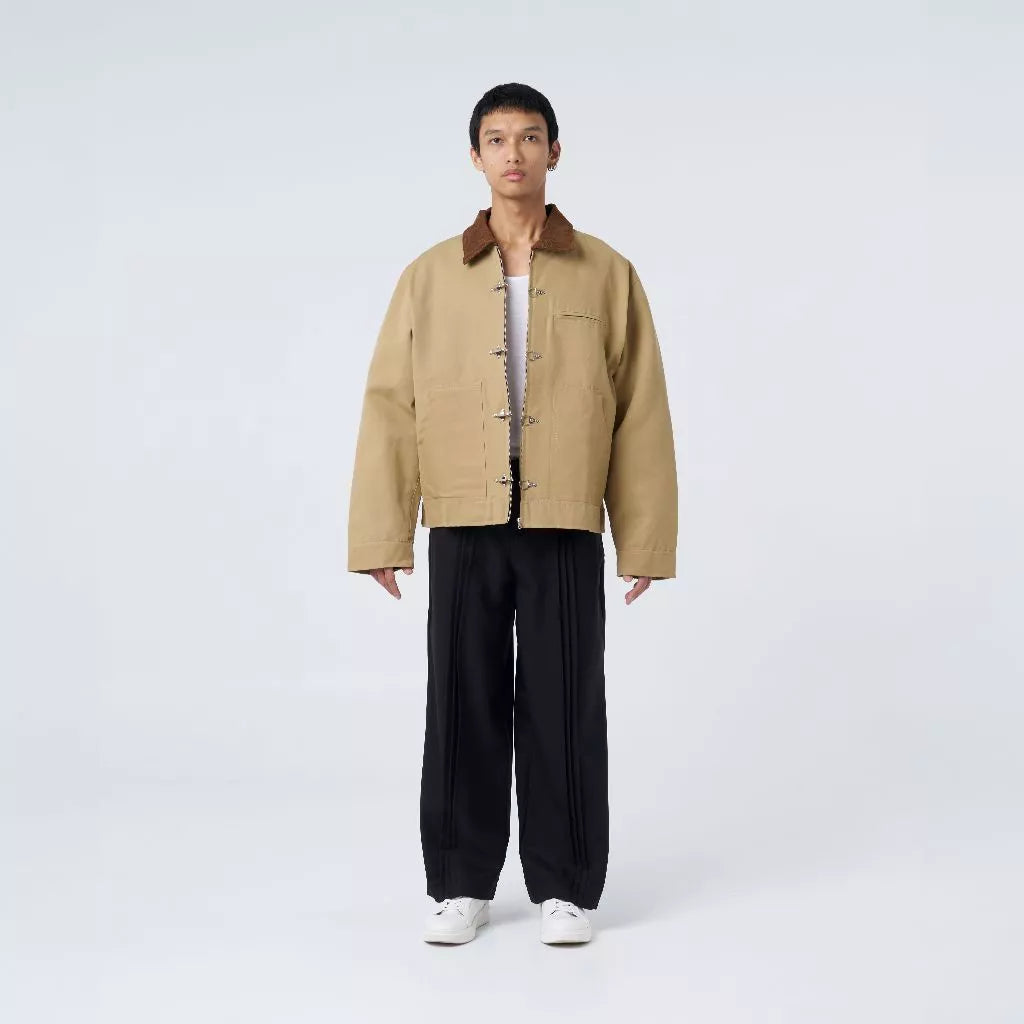 Person wearing a beige fireman clasp jacket by Blee and black pants on a white background