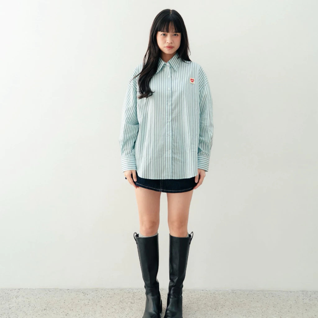 Person wearing a striped blue shirt by notyourcompany, black skirt, and black boots on a plain background