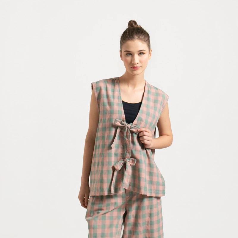 Woman wearing Froyo Vest, a pink and green checkered vest with lace, on a white background