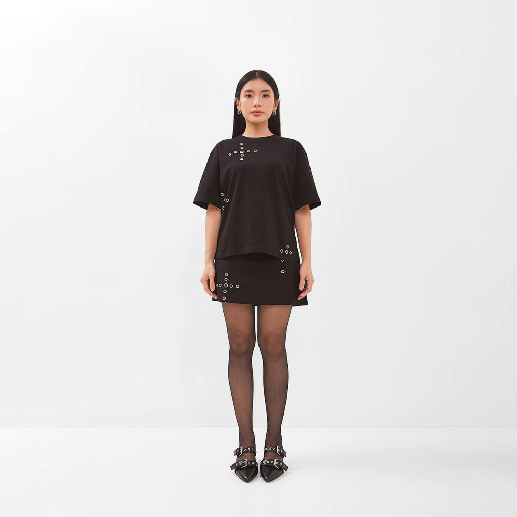 Woman wearing a black t-shirt by Isoos Studios with decorative elements on a white background
