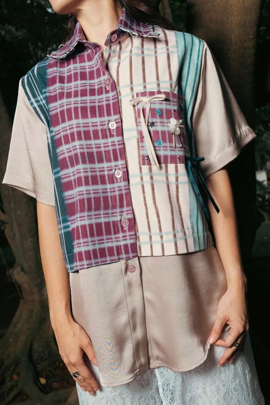 Person wearing a plaid short-sleeve shirt by LR Studio over a beige top with a green vest, standing outdoors.