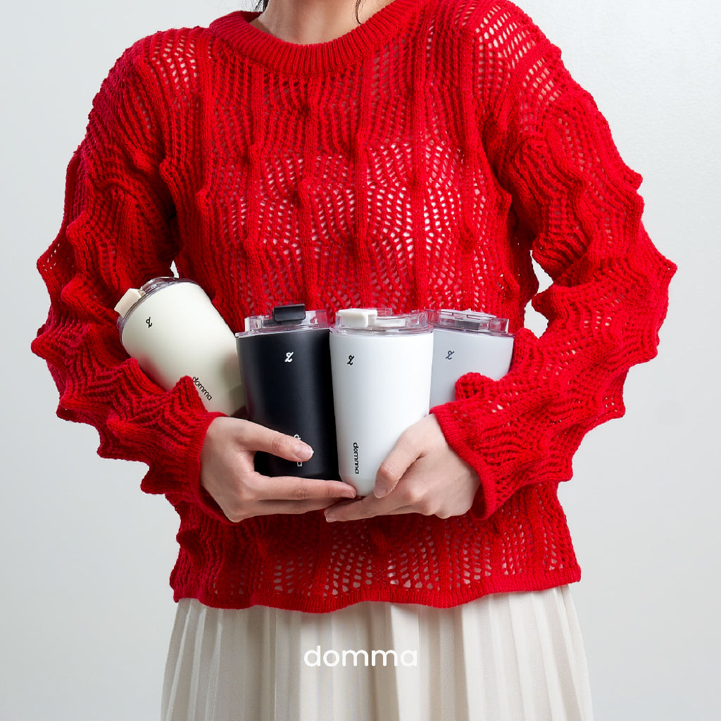 A person in a red knitted sweater holding four stainless steel insulated travel mug, with the brand 'domma'.