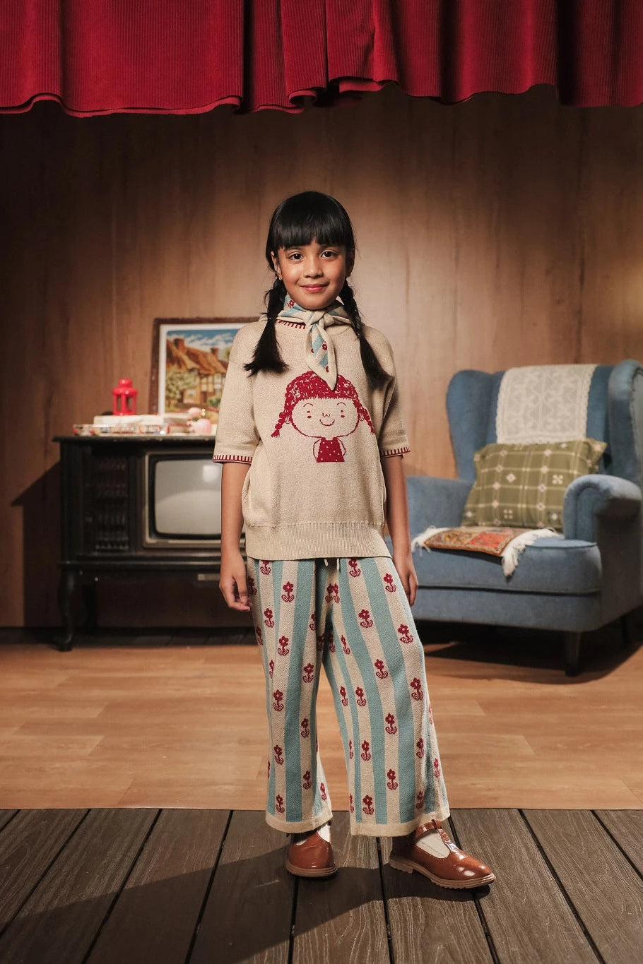 Child wearing a hoodie and striped pants with flower pattern by Sabine & Heem kids clothing in a room with a vintage setup.