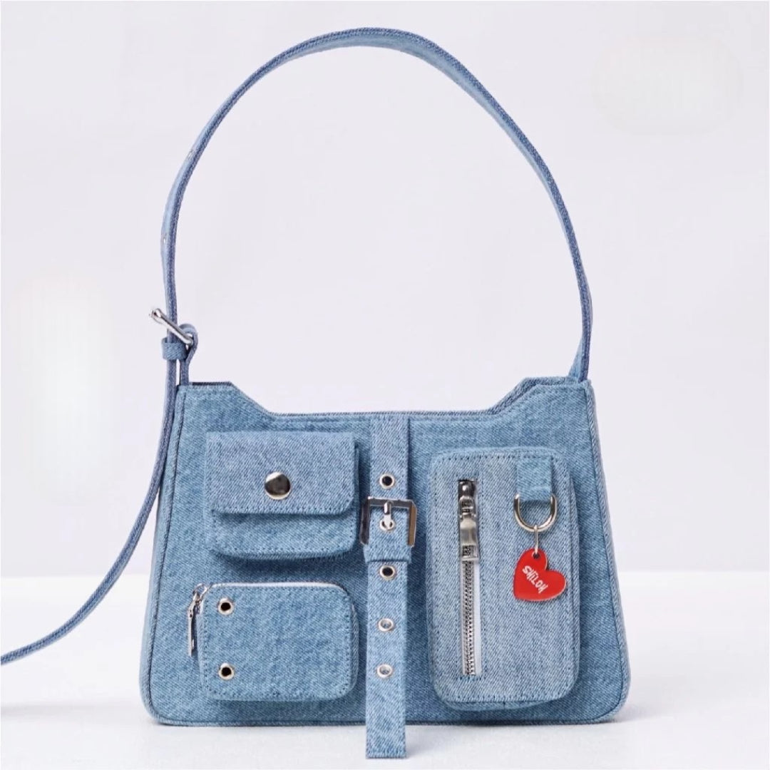 Denim handbag with multiple pockets and a strap on a light gray background
Tas tangan wanita berbahan denim dengan banyak saku dan tali pada latar belakang abu-abu muda