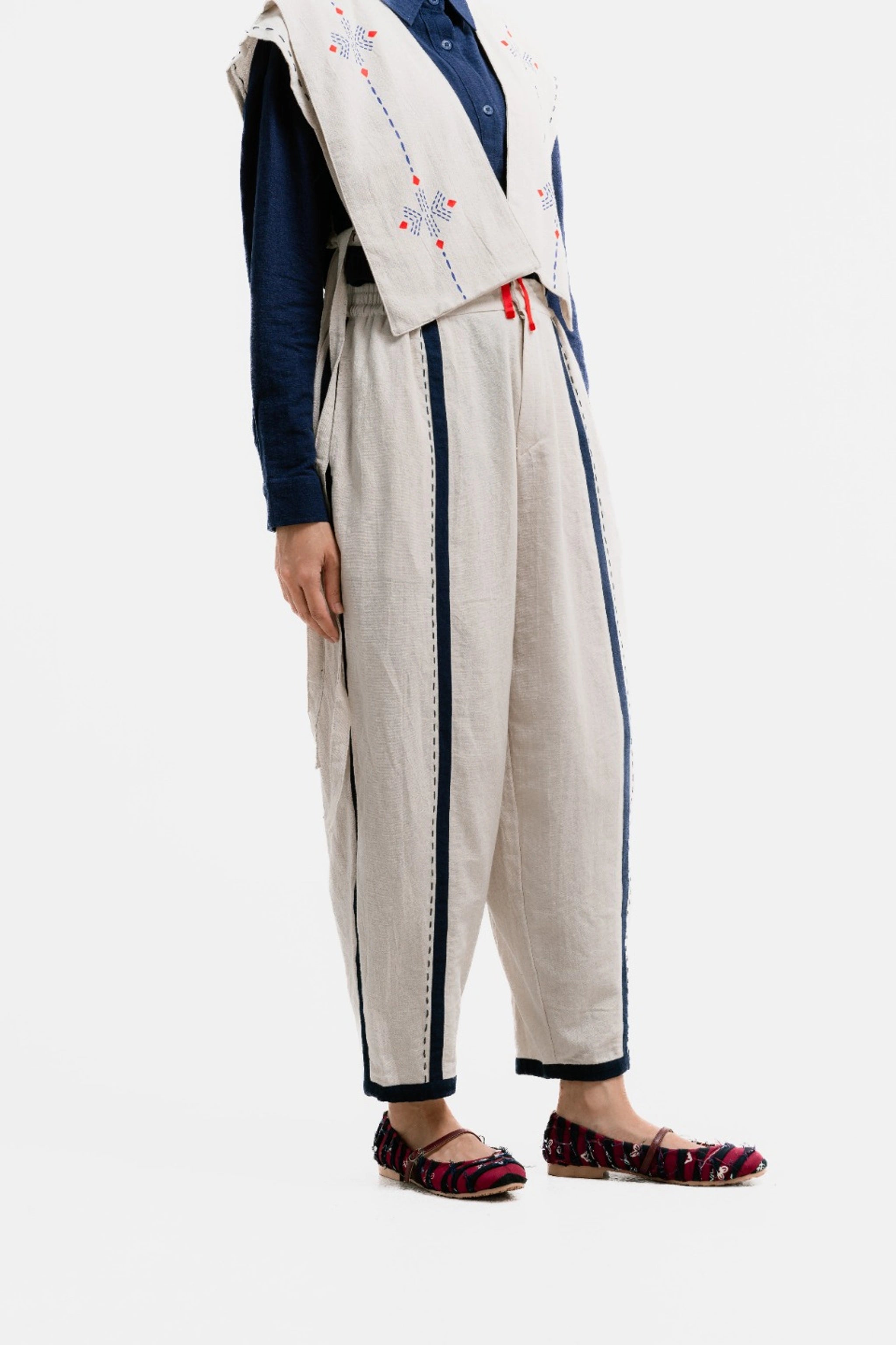 Person wearing a broken white pants with blue accents on a white background