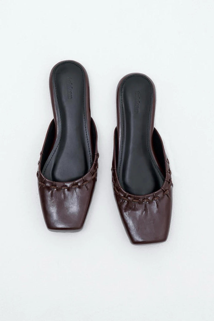 Pair of brown leather mules by Takkan on a white background