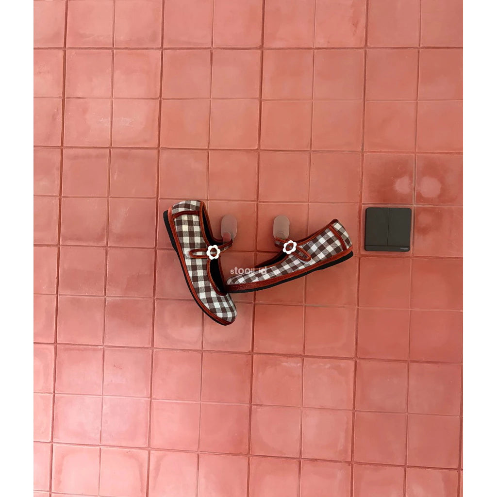 Brown plaid flat shoes by Stooli on a red tiled floor