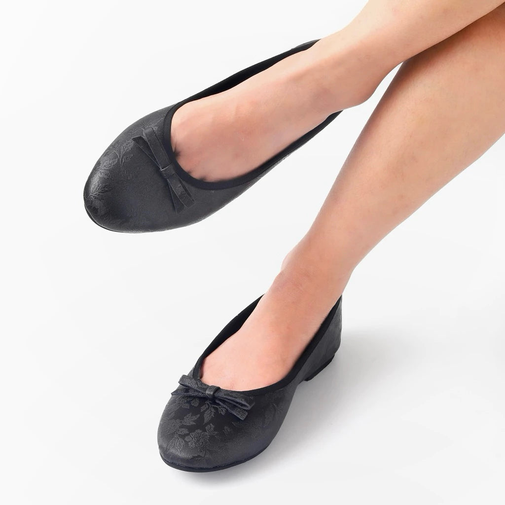 Black ballet flatshoes with bow details on a white background