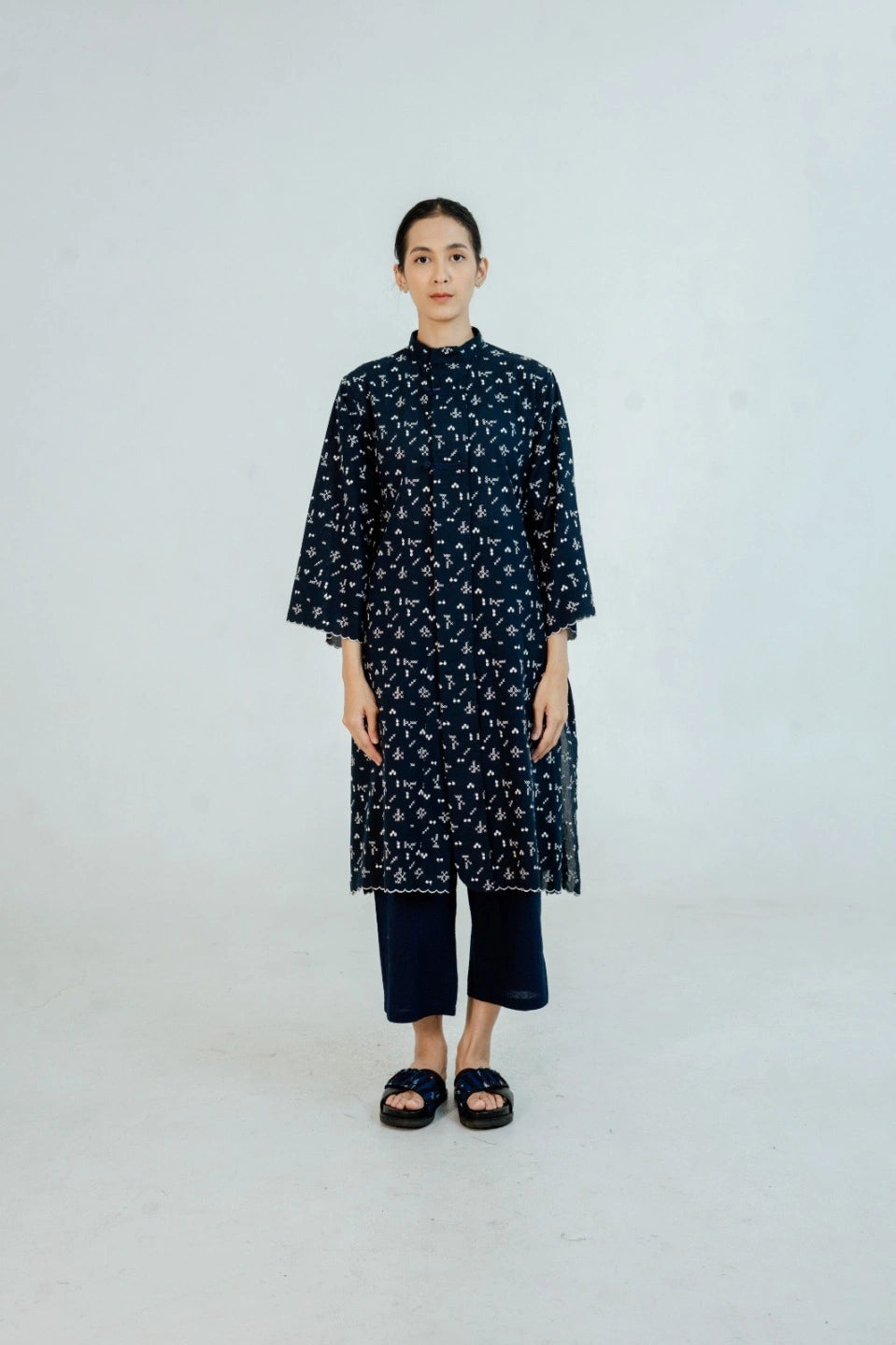 Woman wearing a dark blue floral tunic by Damakara on a white background