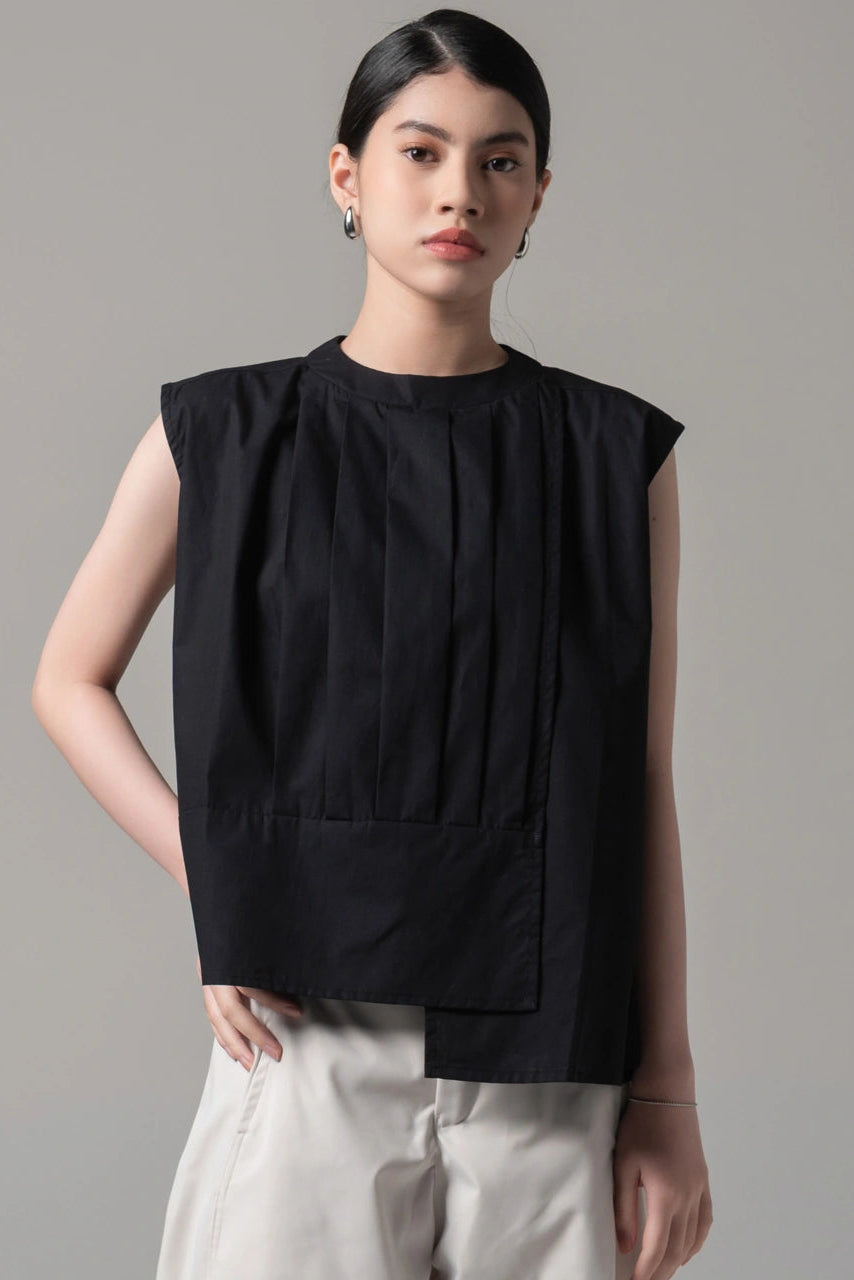 Person wearing a black sleeveless blouse by Kajuaruna with a plain background