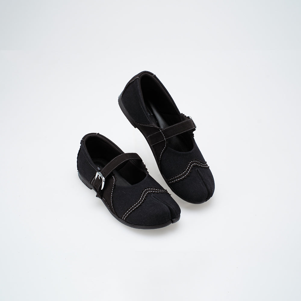Pair of black flat shoes with a strap on a white background