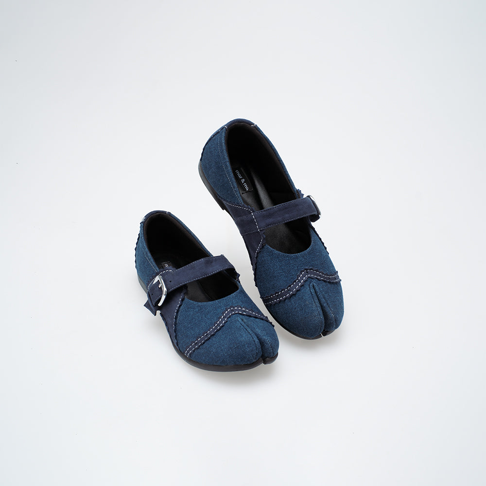 Pair of blue denim flat shoes with a strap on a white background