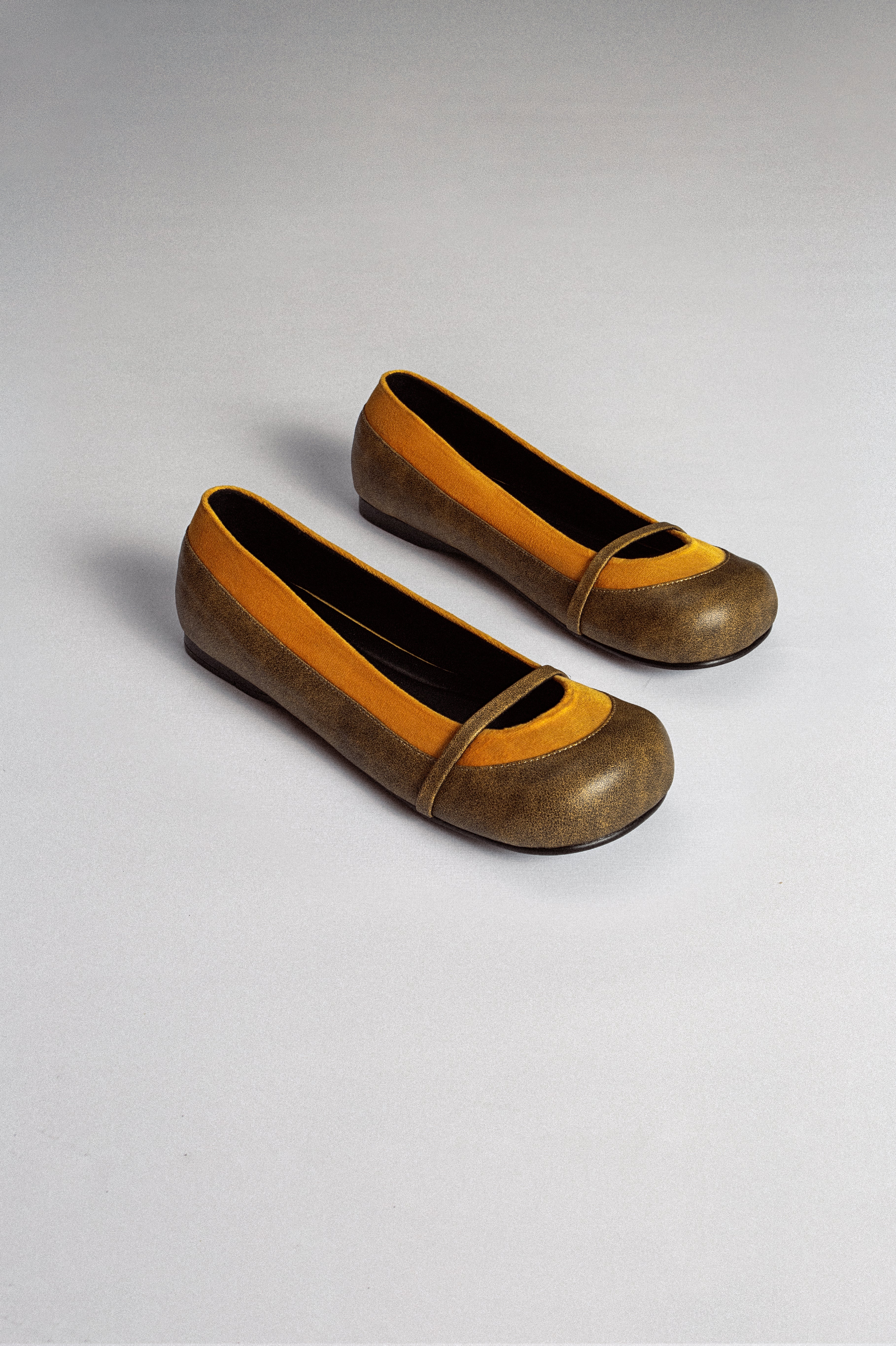 A pair of antique camel line flats with a yellow border at the toe and a flat sole from MTW.
