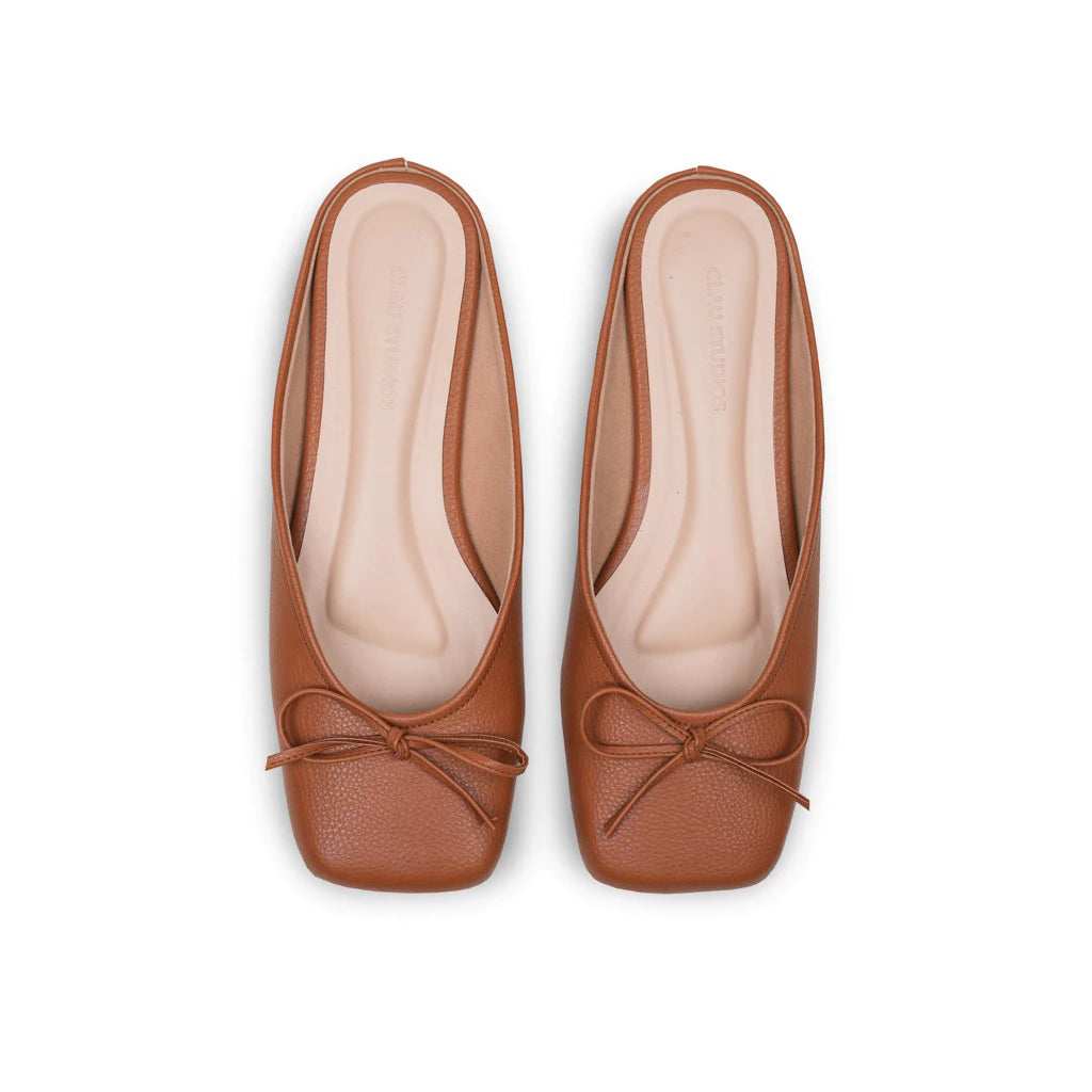 Pair of brown leather flat shoes with bow details on a white background