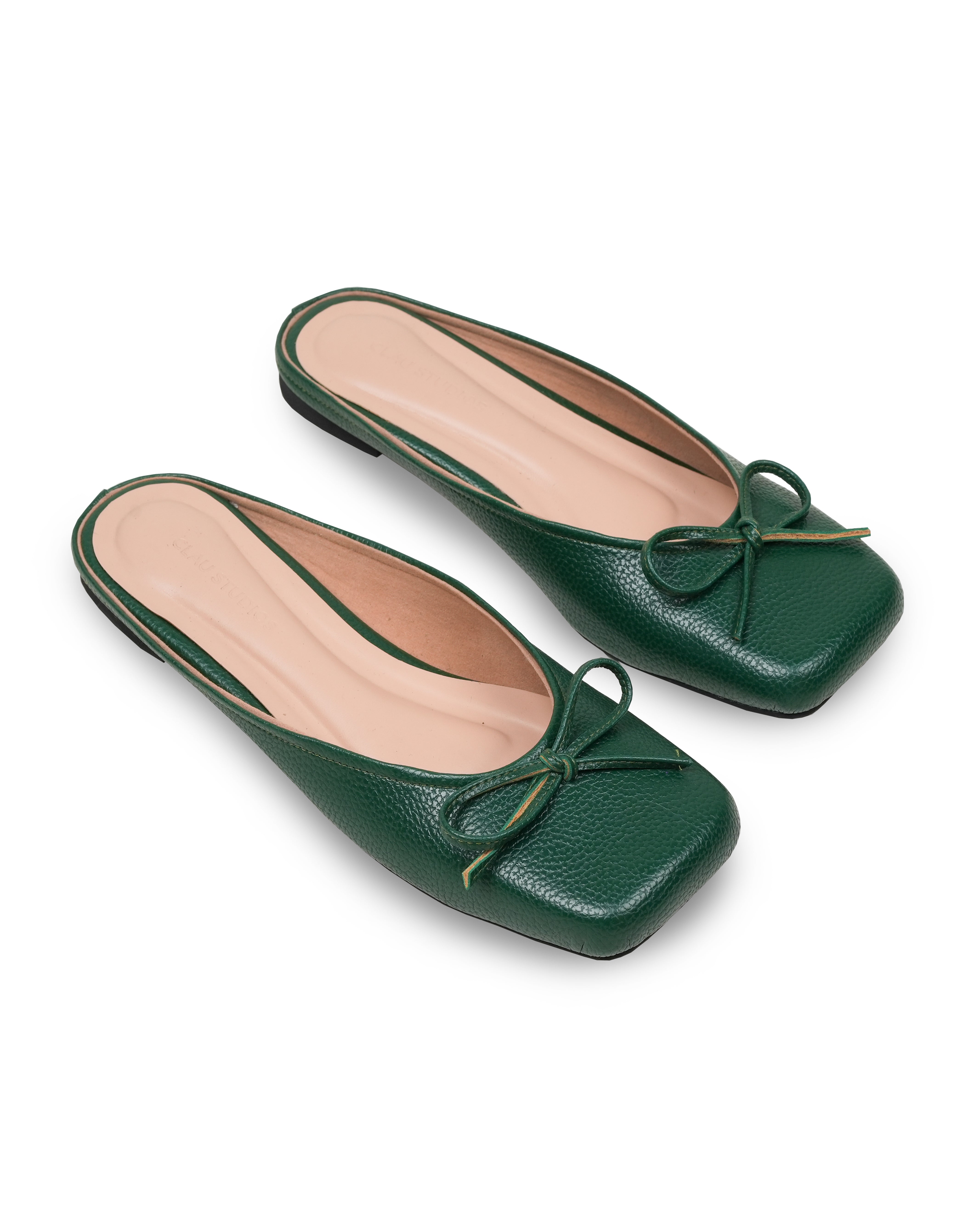 Pair of green leather flat shoes with bow details on a white background