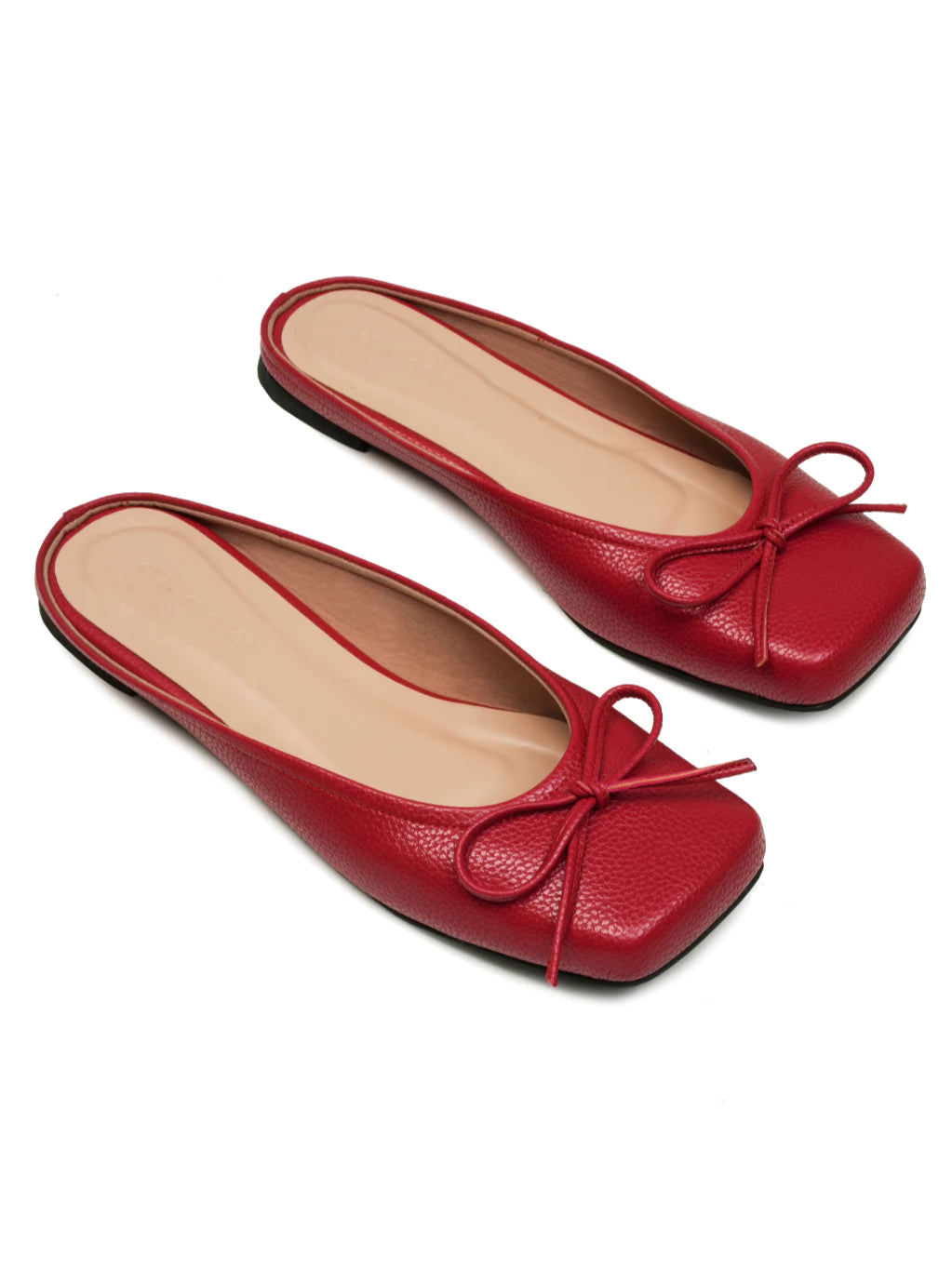 Pair of red flat shoes with a bow details on a white background
