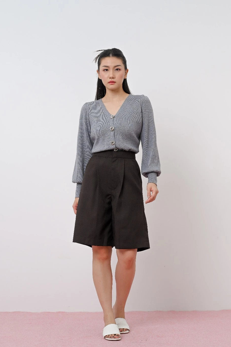 Woman wearing a gray sweater by LR Studio and black skirt against a plain background