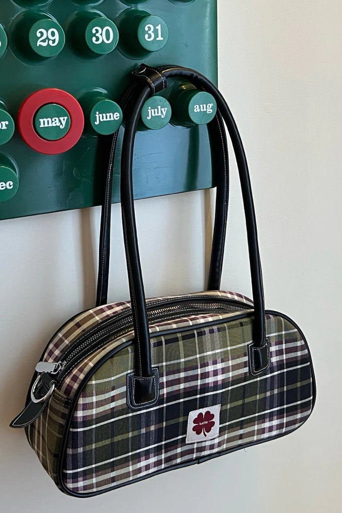 Plaid shoulder bag by Luella with black handles hanging on a wall-mounted calendar.